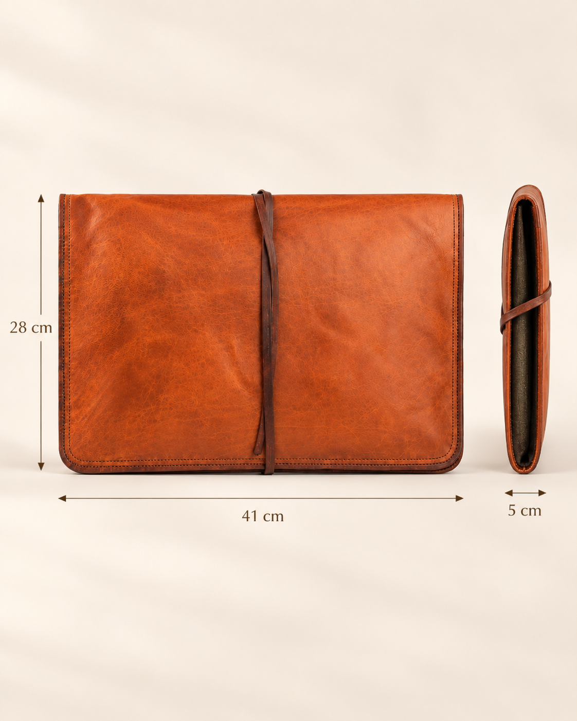 A brown leather laptop sleeve cover or folio shown on a light beige background, with dimension arrows and labels indicating 41 cm width, 28 cm height, and 5 cm depth. The main view shows the front with a strap closure, and a side view shows the folded depth.